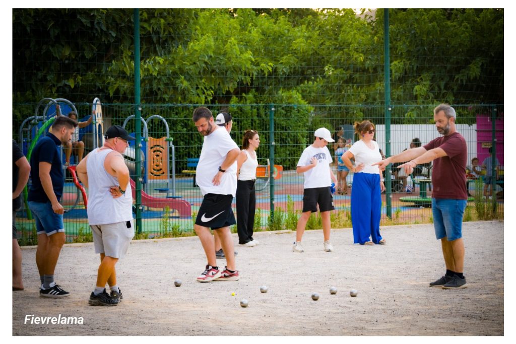 Plusieurs membres du club autour des boules, pendant qu’un joueur désigne le point.