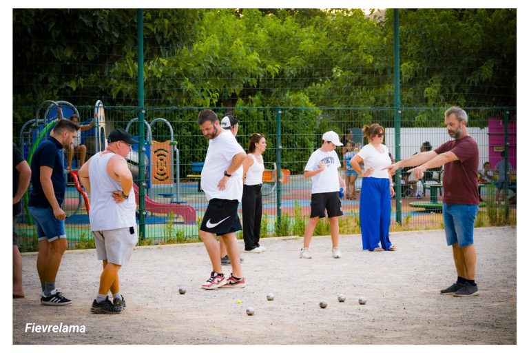 Plusieurs membres du club autour des boules, pendant qu’un joueur désigne le point.