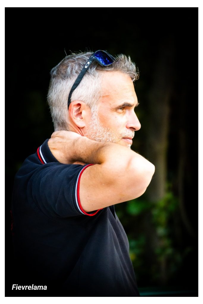 Portrait de profil d’un membre en polo sombre, les lunettes sur la tête et la main derrière la nuque.