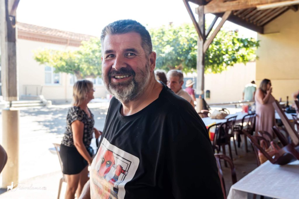 Adhérent souriant sous le préau en bois pendant le repas du club