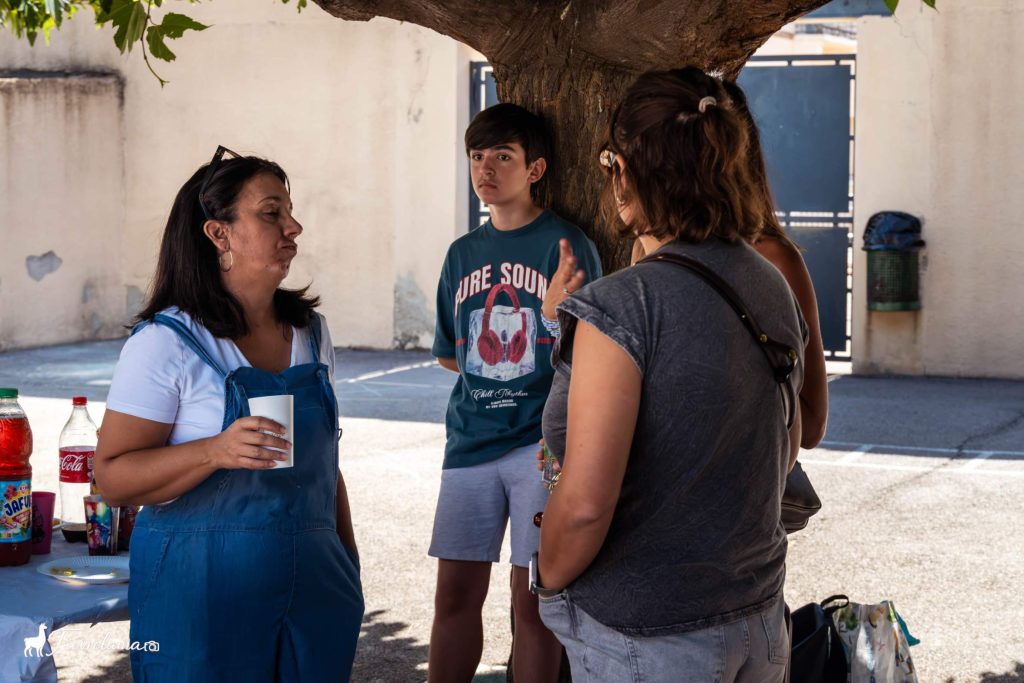 Adhérents et familles qui discutent sous le platane de la cour